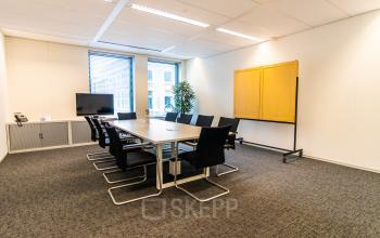 Bright conference room at Parkstraat 83, The Hague Center, featuring a long table with chairs and a presentation board, ideal for office space rental.
