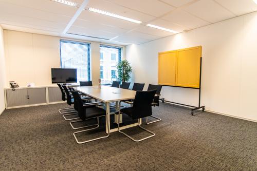 Bright conference room at Parkstraat 83, The Hague Center, featuring a long table with chairs and a presentation board, ideal for office space rental.