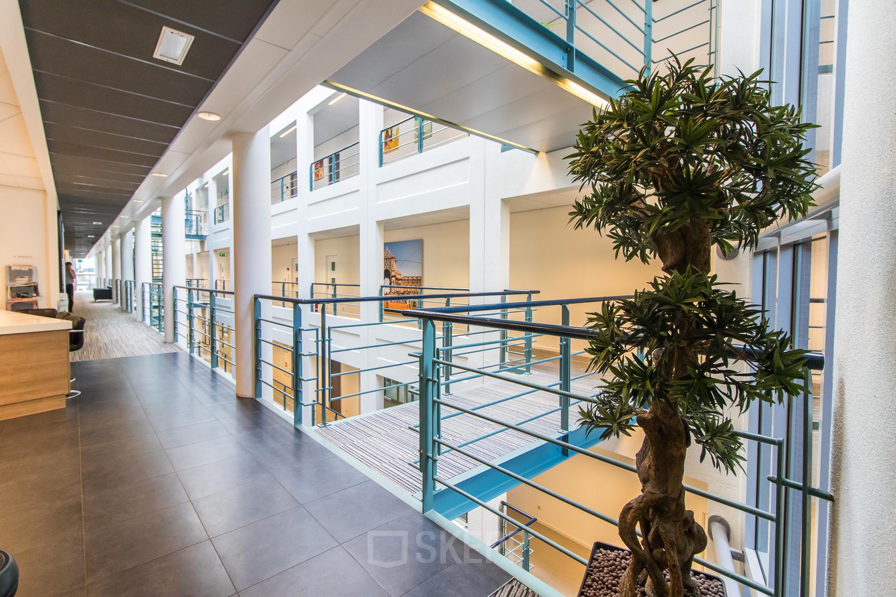Modern office space with metal railings, bright lighting, and a decorative plant at Parkstraat 83 in The Hague Center, perfect for office space rental.