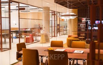 Modern conference room at Zeestraat 70 in The Hague Center, featuring stylish orange chairs around a large table, accented by contemporary lighting and a glass partition. Ideal for office space rental.