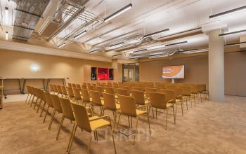 Conference room at Zeestraat 70, The Hague Center, featuring rows of mustard-colored chairs facing a presentation screen, ideal for office space rental needs.