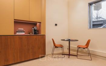 A cozy corner with a small round table and two chairs, perfect for informal meetings or coffee breaks at the office to rent in Zeestraat 70, The Hague Center.