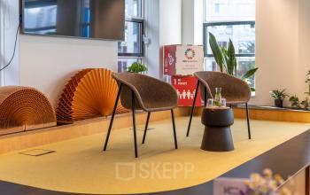 Furnished office space at Fluwelen Burgwal 58, The Hague Center with stylish chairs, small table, and decorative elements. Ideal for office space rental and creative meetings.