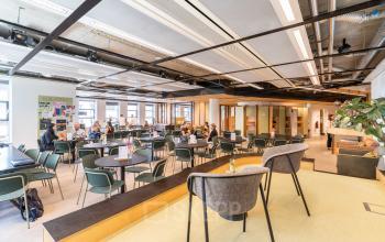 Vibrant office space in The Hague Center with modern furnishings and professionals collaborating at desks. Ideal for office space rental.