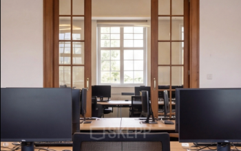 Modern office space rental with ample desks and computers, located at Mauritskade 9 in The Hague Center.