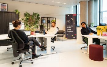 Bright, furnished office space with three people collaborating around desks at Waldopstraat 5, The Hague Center, ideal for office space rental.