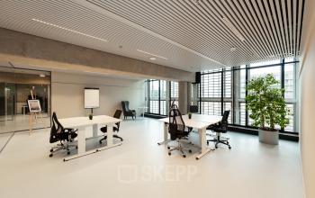 Spacious office at Waldopstraat 5, The Hague Center, featuring modern furniture with desks and chairs by large windows. Ideal office space rental for professionals seeking a bright, open environment.