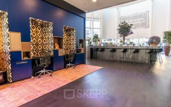 Stylish workspace interior at Kalvermarkt 53, The Hague Center, featuring modern workstations with patterned panels and bar seating area.