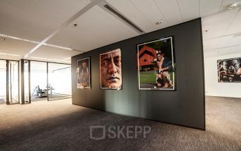 Art-adorned walkway in a modern office space rental at Kalvermarkt 53, The Hague Center, with visible workspaces in the background.