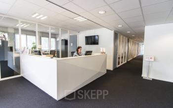 Spacious office to rent at Platinaweg 25, The Hague Escamp featuring a modern reception desk with a person assisting visitors.