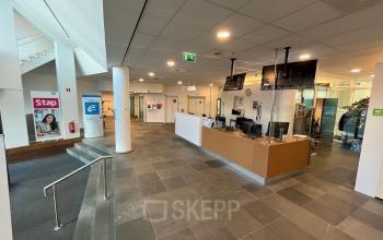 Reception area at Platinaweg 10, The Hague Escamp with a modern desk, banner displays, and accessible walkways. Ideal office space rental with a welcoming environment.