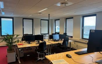 Bright and airy office space rental at Platinaweg 10, The Hague Escamp, featuring desks, computers, and a plant by the window.