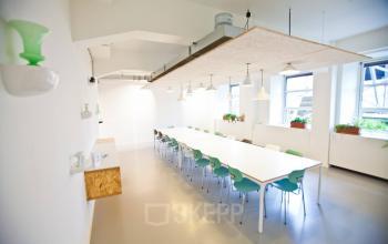 Bright, modern workspace with long tables and colorful chairs at Zuid Hollandlaan 7, The Hague Haagse Hout, available for office space rental.
