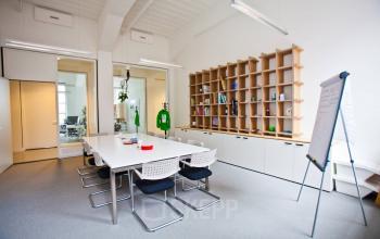 Spacious office space rental at Zuid Hollandlaan 7, The Hague Haagse Hout featuring a long table, whiteboard, and organized shelving unit.