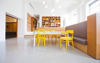 Modern, well-lit office space rental at Zuid Hollandlaan 7, The Hague Haagse Hout, featuring a cozy lounge area with bookshelves and stylish yellow chairs.