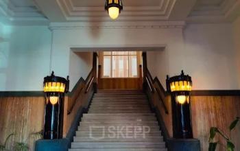 Interior photo of a well-lit entrance with a grand staircase and wooden accents, ideal for rent office space in The Hague.