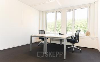 Bright office space with two desks and chairs, large windows offering greenery views, ideal for rent office space at Bezuidenhoutseweg 161, The Hague Haagse Hout.