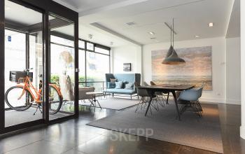 Office space for rent at Bezuidenhoutseweg 161, The Hague Haagse Hout, featuring a modern, furnished interior with a table, chairs, and a couch by the window.