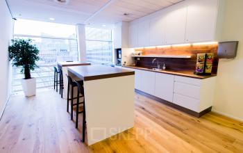 Modern office space rental at Jan Pietersz. Coenstraat 7, The Hague Haagse Hout with a wooden floor and a furnished kitchen area.