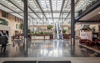 Spacious interior of Prinses Margrietplantsoen 25 in The Hague, showcasing a modern open floorplan with sleek flooring, comfortable seating, and green accents; perfect for office space rental.