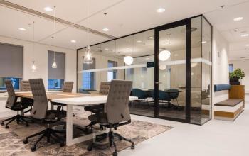 Stylish office space rental at Prinses Margrietplantsoen 25, The Hague Haagse Hout. Modern design with sleek furnishings, open workspace, glass-walled conference area, and elegant lighting creating a professional atmosphere.