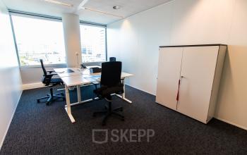 Furnished office space for rent at Schenkkade 50, The Hague Haagse Hout, featuring a minimalist design with desks and chairs, overlooking city views.