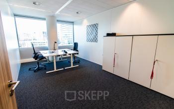 Bright, furnished office space at Schenkkade 50, The Hague Haagse Hout, ideal for rent. The room features desks and chairs, large windows, and ample storage cabinets.