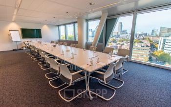 Spacious conference room at Schenkkade 50 in The Hague Haagse Hout with large tables, modern chairs, and cityscape views, ideal for office space rental.