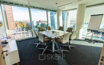 A bright conference room with a large table and chairs, offering a view over The Hague from Schenkkade 50. Ideal for office space rental.