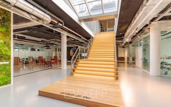 Modern office space rental at Oude Middenweg 3-19, The Hague, featuring a stylish staircase with warm lighting and green wall accents.
