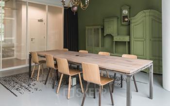 Modern office space rental at Oude Middenweg 3-19, The Hague, featuring a stylish wooden conference table and elegant, vintage green walls.