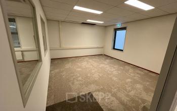 Spacious office with large windows and carpeted floors at Oder 20, The Hague. Ideal for office space rental to customize as needed.
