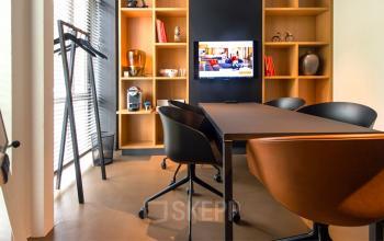 Elegantly appointed office space rental at President Kennedylaan 19, The Hague, with a polished meeting table and chic shelving.