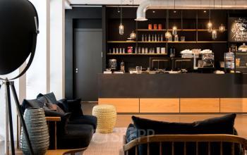 Modern office space rental at President Kennedylaan 19, The Hague, featuring a cozy lounge area with chic furnishings and a coffee bar.