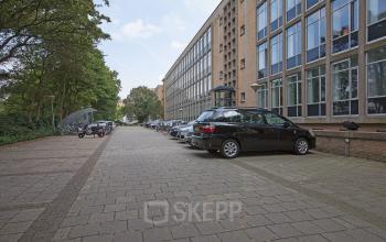 Exterior of President Kennedylaan 19 office building in The Hague Statenkwartier with parked cars in front.