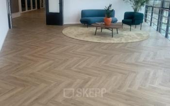 Bright office lounge area at Johan de Wittlaan 3-7, The Hague Statenkwartier, featuring a seating arrangement with two chairs and a sofa on a light rug.