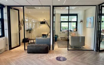 Modern office space with glass-walled meeting rooms at Johan de Wittlaan, The Hague. Ideal for office space rental with stylish furniture and natural lighting.