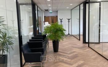 Modern corridor with glass walls and chairs on Johan de Wittlaan 3-7, ideal for office space rental in The Hague Statenkwartier.