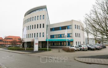 Exterior view of a modern office building at Keulenstraat 12, Deventer, with parking spaces in front.