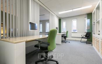 Modern office space rental at Keulenstraat 12 in Deventer featuring spacious desks with green chairs and natural light from large windows.