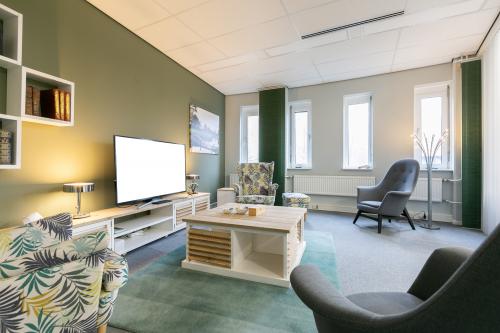 Interior of an office at Keulenstraat 12 in Deventer with comfortable seating, a TV, bookshelves, and ample light from windows.