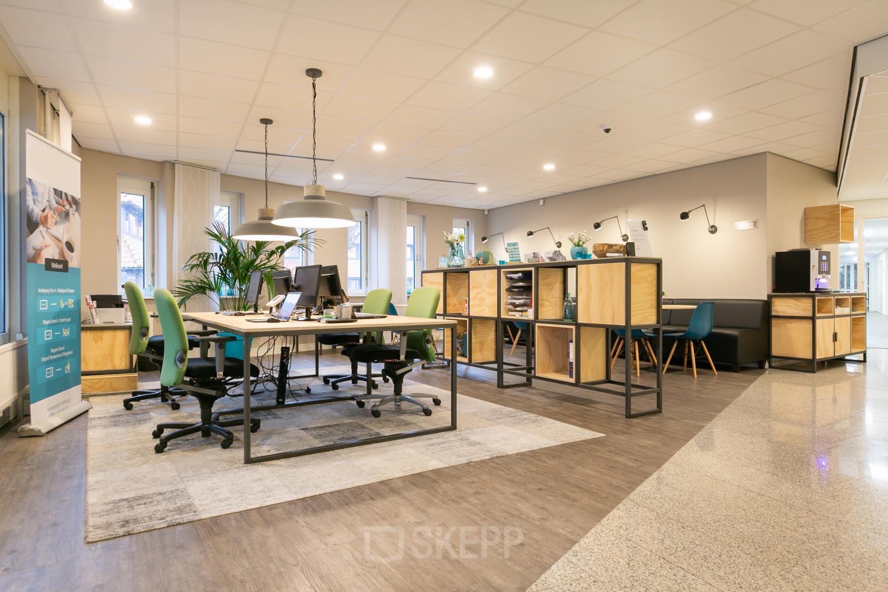 Modern workspace with green chairs, desks, and shelf units at Keulenstraat 12, Deventer. Bright lighting and plants enhance the office space rental atmosphere.