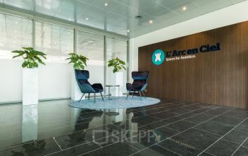 Office interior at Zutphenseweg 29, Deventer, featuring a sleek waiting area with chairs and plants, ideal for office space rental.
