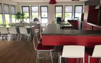 Modern office lounge at Keulenstraat 15, Deventer, featuring red counters and white seating suitable for meetings or breaks, ideal for office space rental.
