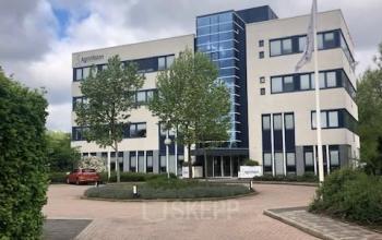 Exterior view of office building at Keulenstraat 15, Deventer, suitable for office space rental, featuring a modern facade and ample parking space.