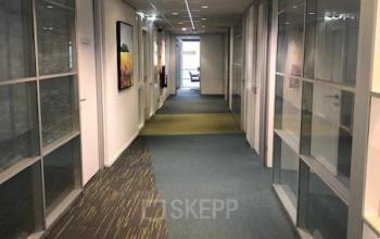 Bright interior hallway at Keulenstraat 15, Deventer, featuring glass panel walls and a long carpeted corridor, ideal for office space rental.