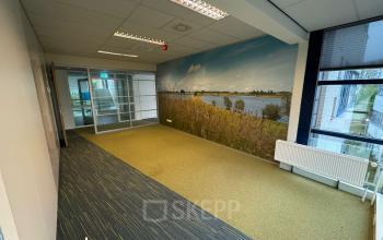 Office space at Keulenstraat 15, Deventer, featuring large windows and a scenic wall mural, ideal for office space rental.