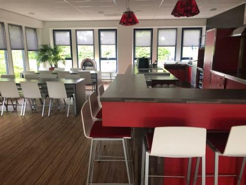 Modern office lounge at Keulenstraat 15, Deventer, featuring red counters and white seating suitable for meetings or breaks, ideal for office space rental.