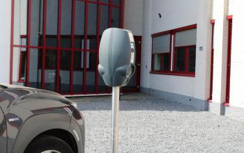 Exterior view of office space for rent at Keulenstraat 1, Deventer, featuring a parking area with an electric vehicle charging station.