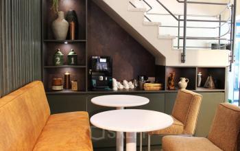 Modern office lounge at Keulenstraat 12 in Deventer, featuring cozy seating and a coffee machine beneath a stylish staircase.